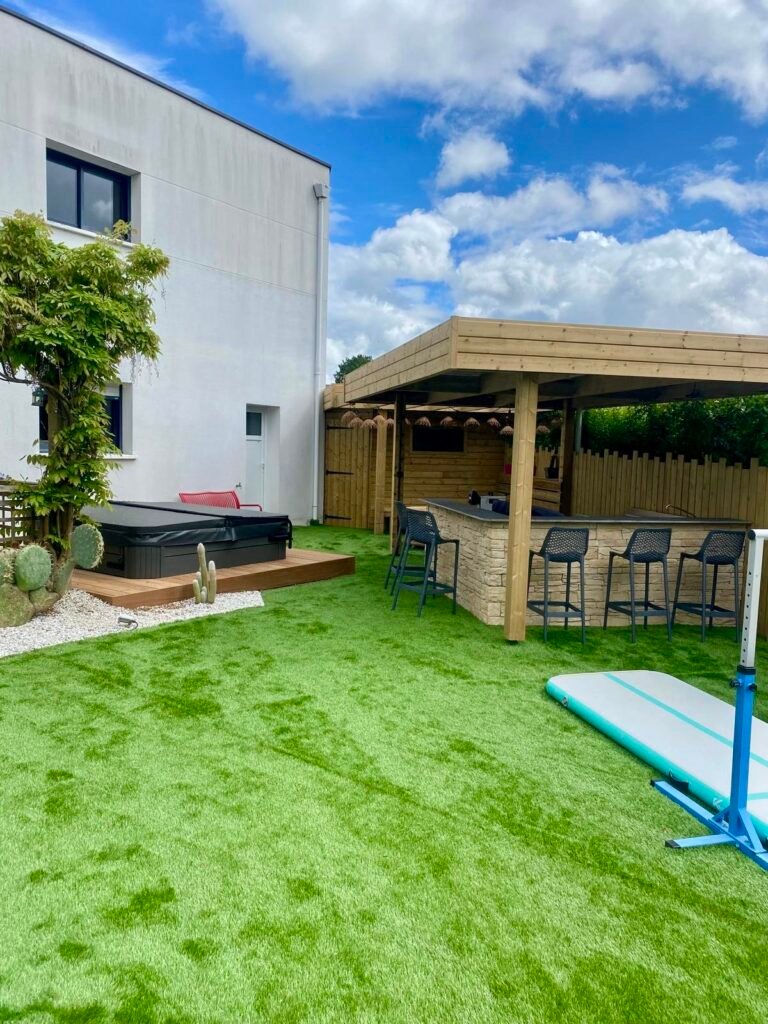 SPA avec aménagement en bois et cuisine extérieure - gazon synthétique