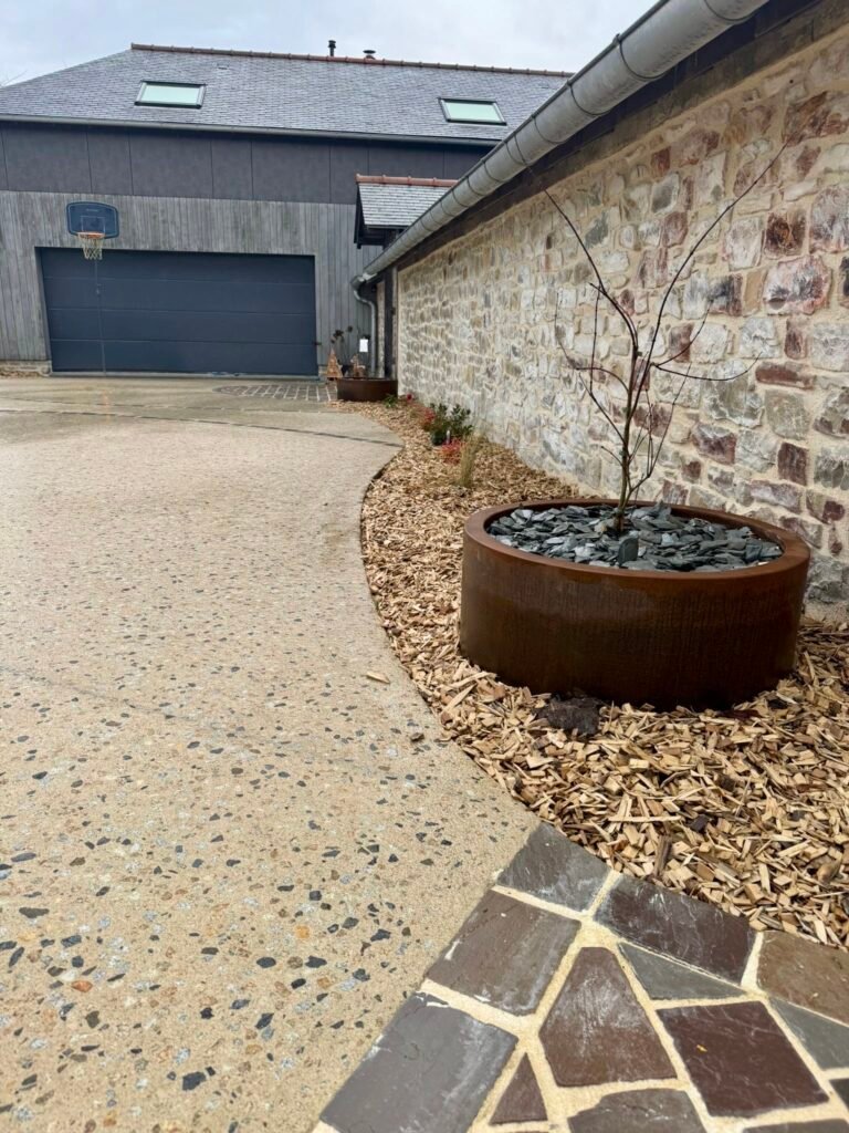 Cour en béton érodé - pavés en grès multicolore - jardinières en corten
